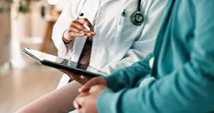 Clinician in scrubs reviewing notes on a tablet