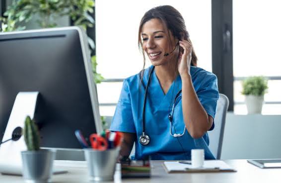 Nurse taking a call at a computer desk