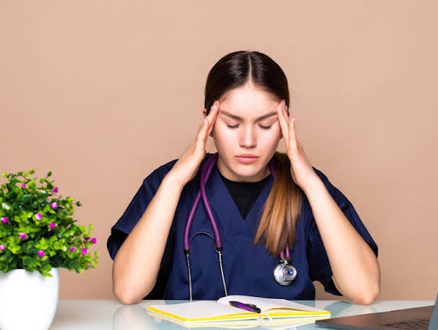 Stressed student studying with a stethoscope nearby